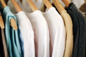 Sweaters and t-shirts hanging on a rack in a clothing store
