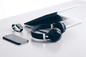 A laptop, smartphone, smartwatch and headphones placed on a desk