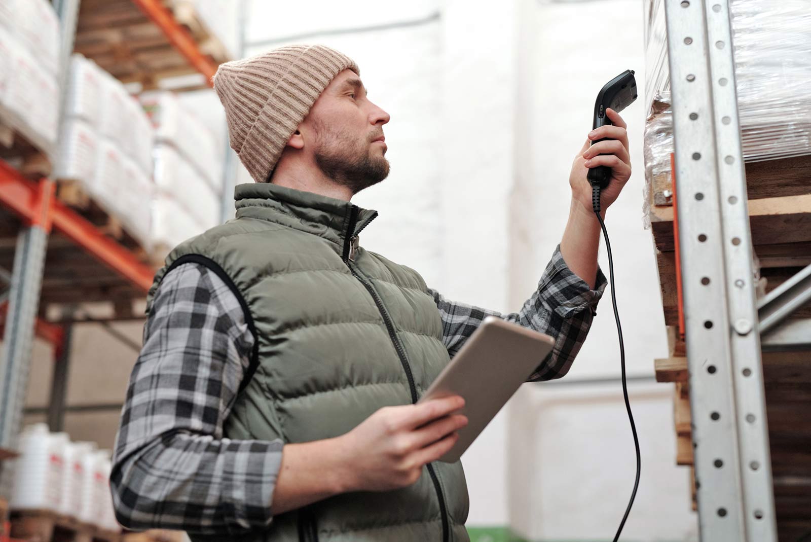 A man checking warehouse inventory with a handheld tablet computer